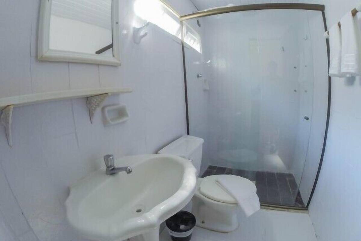Un baño con lavamanos blanco, inodoro y ducha con mampara de vidrio.