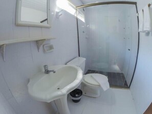 A bathroom with a white sink, toilet, and glass-enclosed shower. - Pousada Campestre São Lourenço (Sao Lourenco)