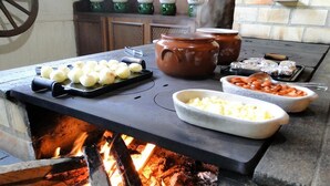 Un horno de piedra con alimentos como papas y queso sobre una encimera.
