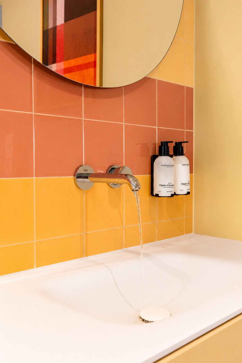 A bathroom with a white sink, a chrome faucet, and two bottles of Marie-Stella shower gel on the wall.