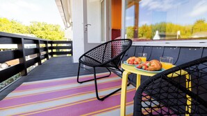 A balcony with a table set for breakfast, a chair, and a view of greenery. - Domburg4you (Domburg)