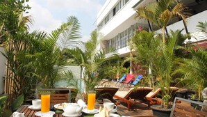 A wooden deck with a breakfast setup including plates, cups, and a glass of orange juice. - MEN's Resort & Spa - Caters to Gay Men (Siem Reap)