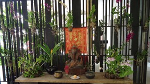 A shrine with a statue, incense, and offerings on a table, surrounded by potted plants and a decorative screen. - MEN's Resort & Spa - Caters to Gay Men (Siem Reap)