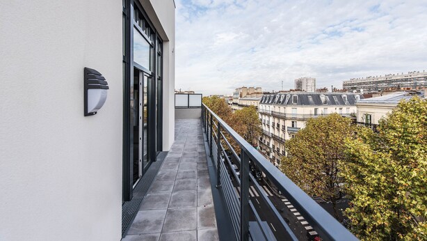 A balcony with a view of city buildings and trees. - Les Appartements Paris Clichy (Clichy)