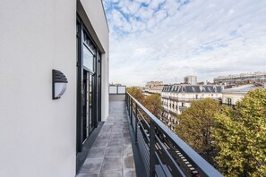 A balcony with a view of city buildings and trees.