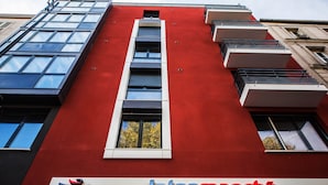A building with a red facade, a sign reading "Intermarché," and a logo for "Les Mousquetaires." - Les Appartements Paris Clichy (Clichy)