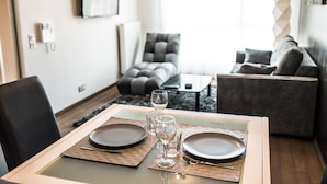 A dining area with a table set for two, a sofa, and a coffee table in a modern living space. - Les Appartements Paris Clichy (Clichy)