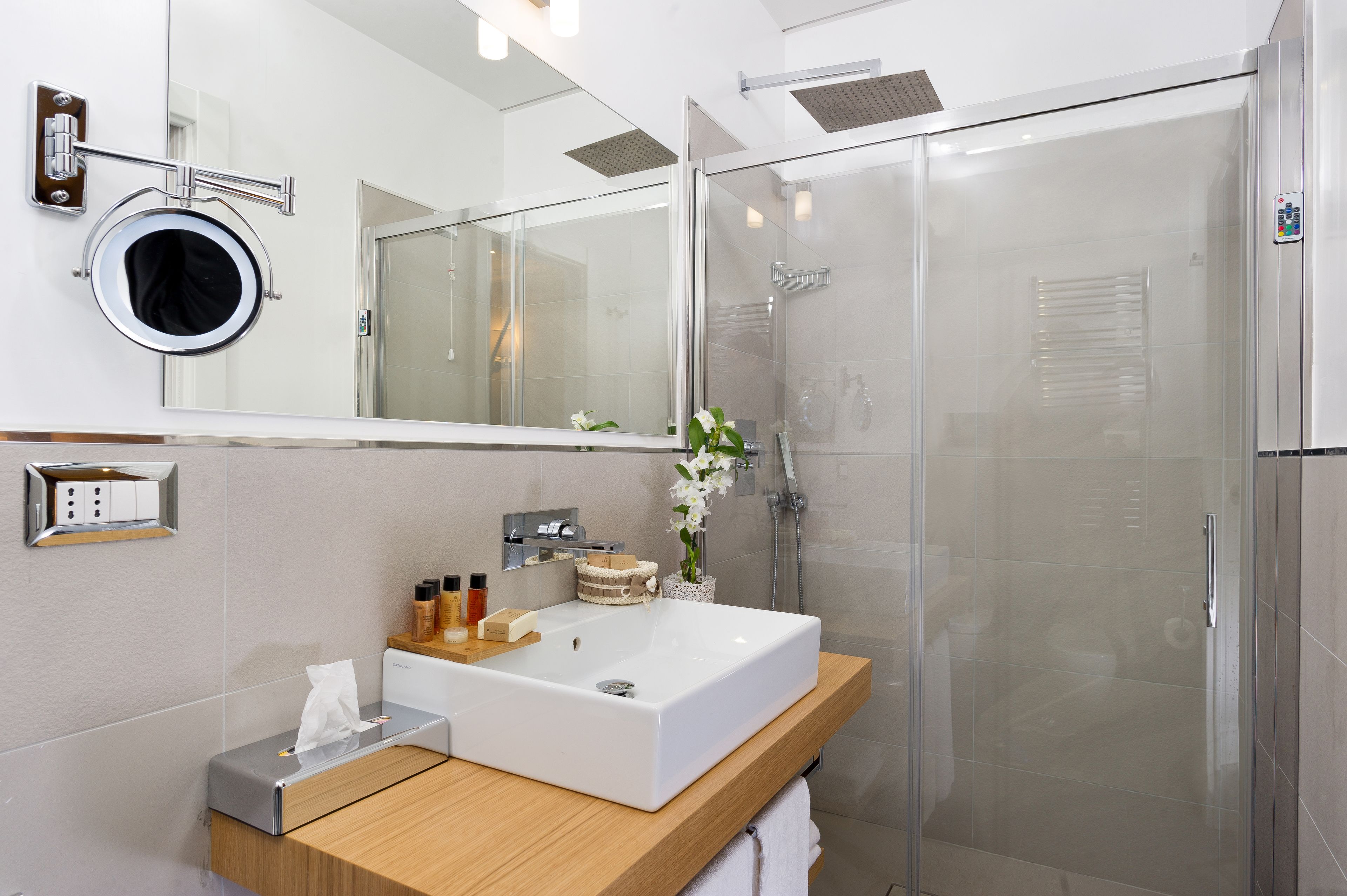 Un bagno moderno con uno specchio grande, un lavandino e una cabina doccia in vetro.