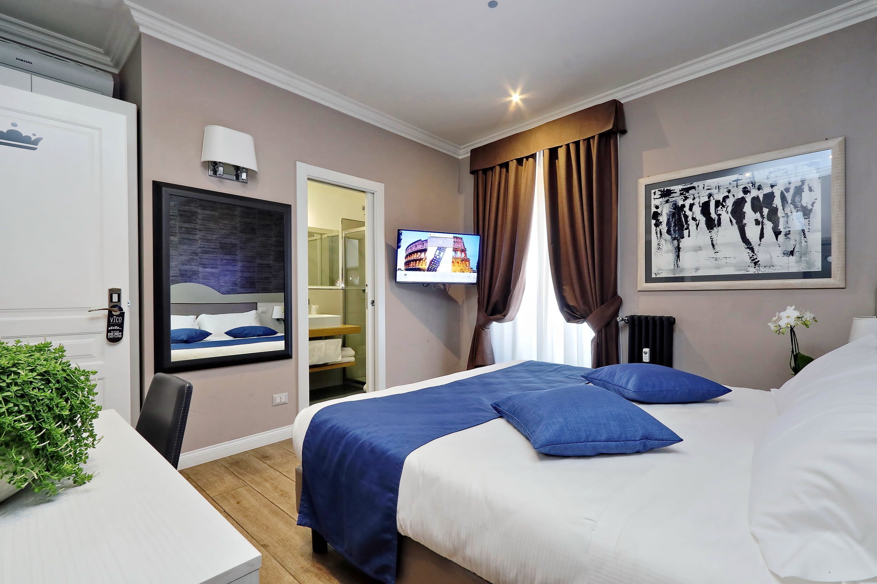 Une chambre d’hôtel avec un lit, une télévision, une salle de bain et une plante.