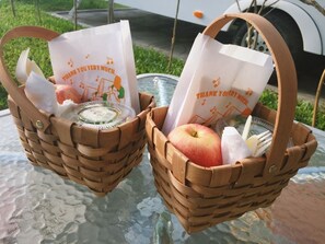 Zwei gewebte Körbe mit Trägern, jeder mit einer Papier-Tasche, die ein Notendesign und den Text 'THANK YOU VERY MUCH' zeigen.