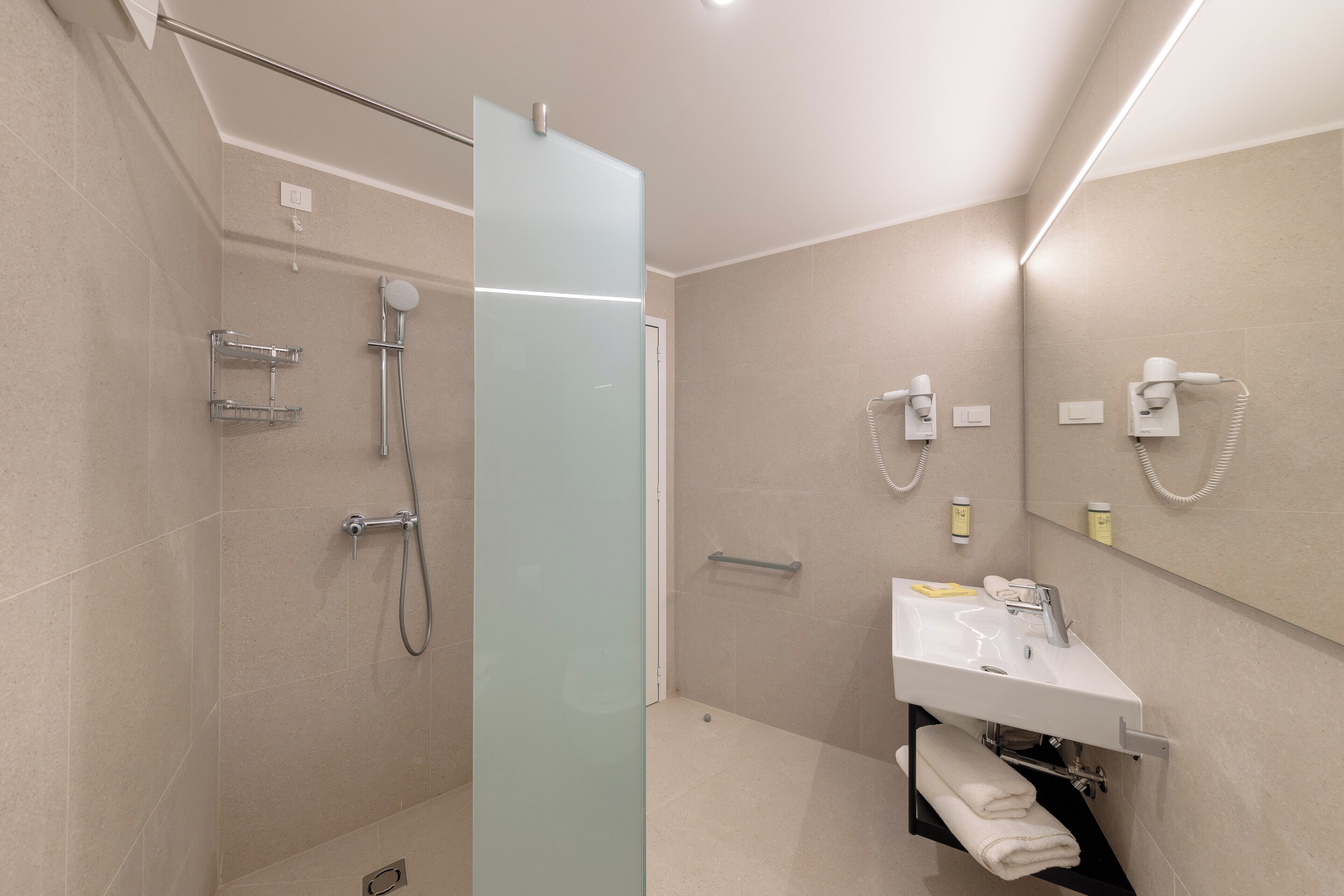 A modern bathroom with a glass shower enclosure, a white sink, and a towel rack.