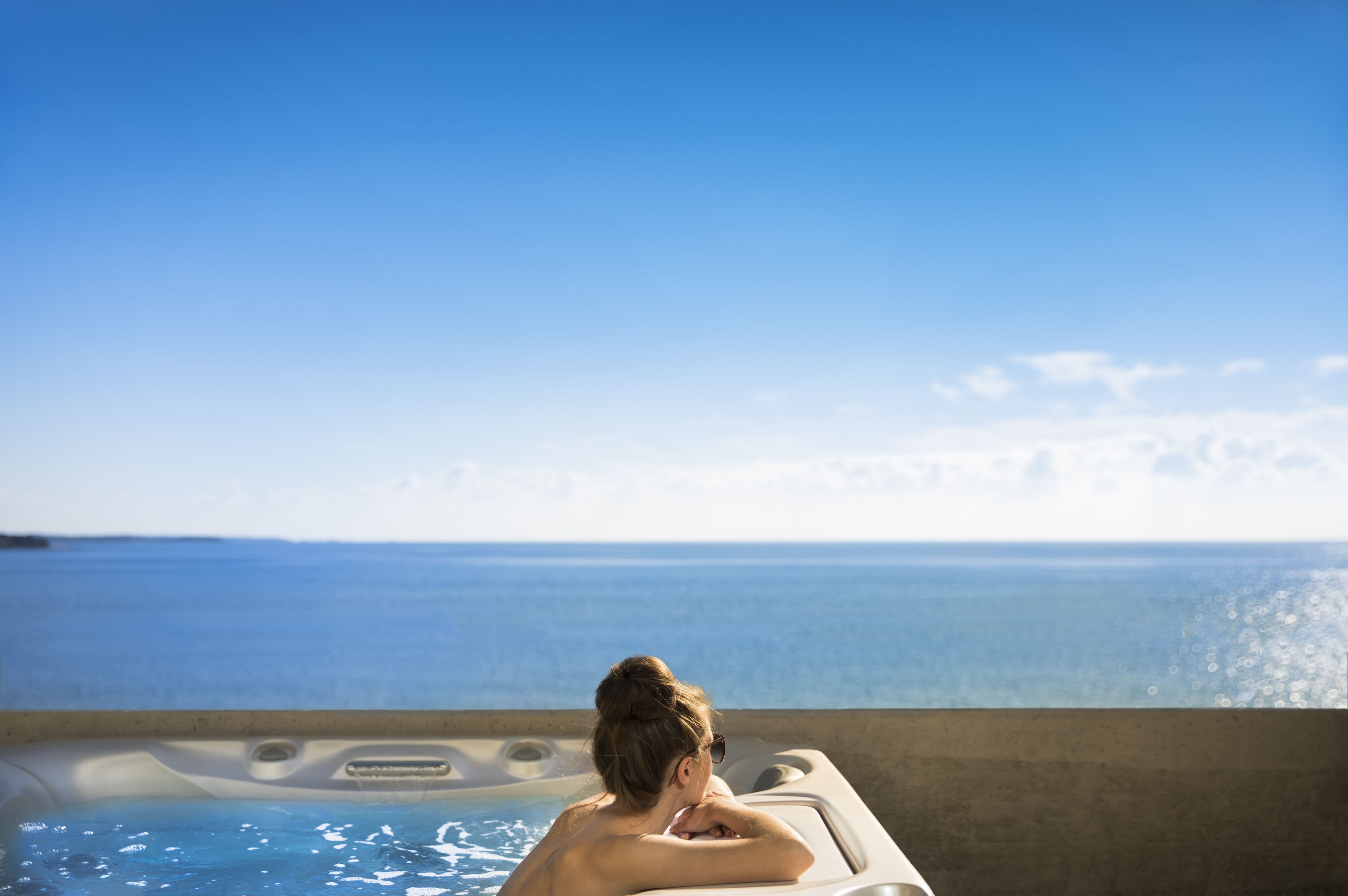 A person relaxing in a hot tub with a view of the ocean.