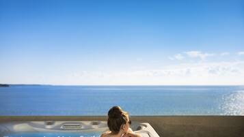 A person relaxing in a hot tub with a view of the ocean.