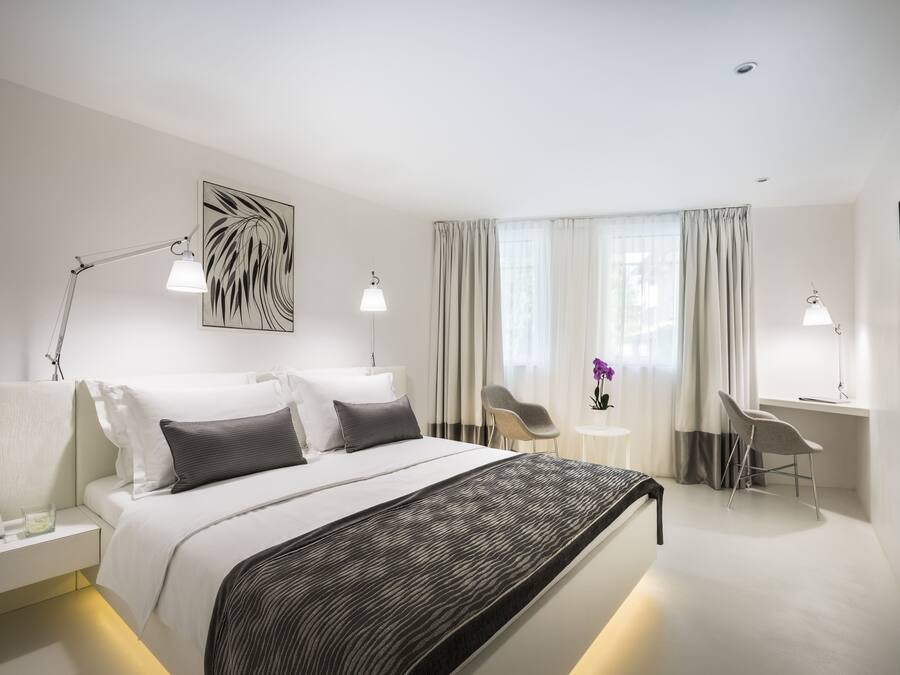 Una habitación de hotel moderna con una cama grande, mesitas de noche, un escritorio y una silla.