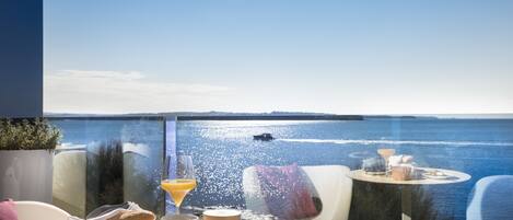 A balcony with a table set for breakfast, overlooking a body of water.