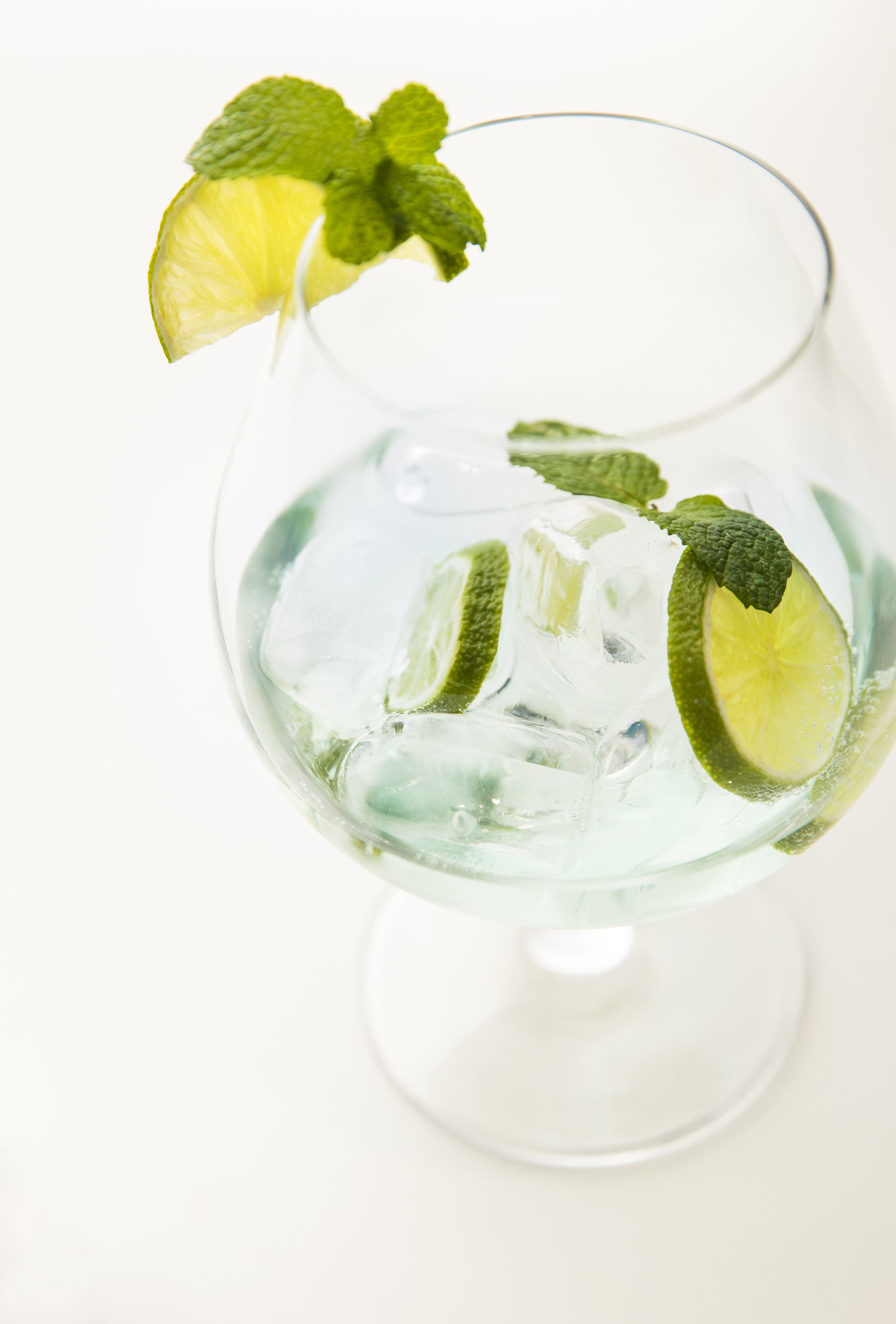 A glass with ice cubes and lime slices.