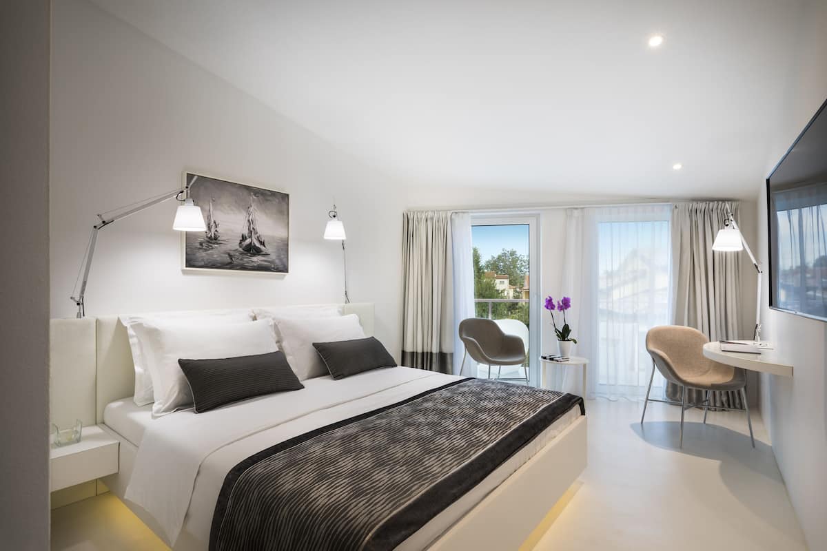 A modern hotel room with a large bed, a desk, and a chair.