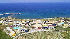 An aerial view of a coastal resort with multiple buildings, a swimming pool, and a marina.