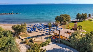 A beachside hotel with a pool area, umbrellas, and a view of the sea.
