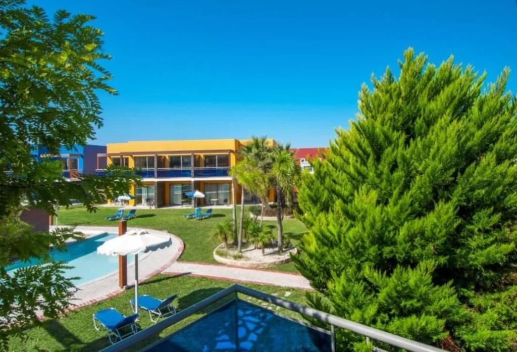 A pool area with lounge chairs and a building in the background.