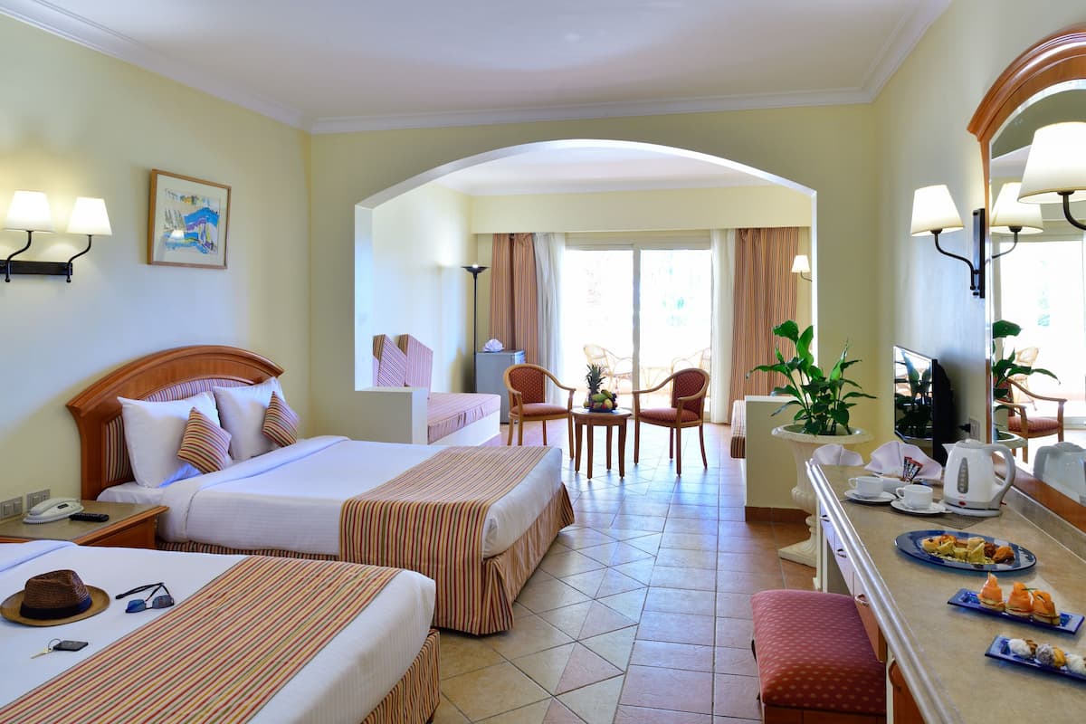 A hotel room with two beds, a dining area, and a TV.
