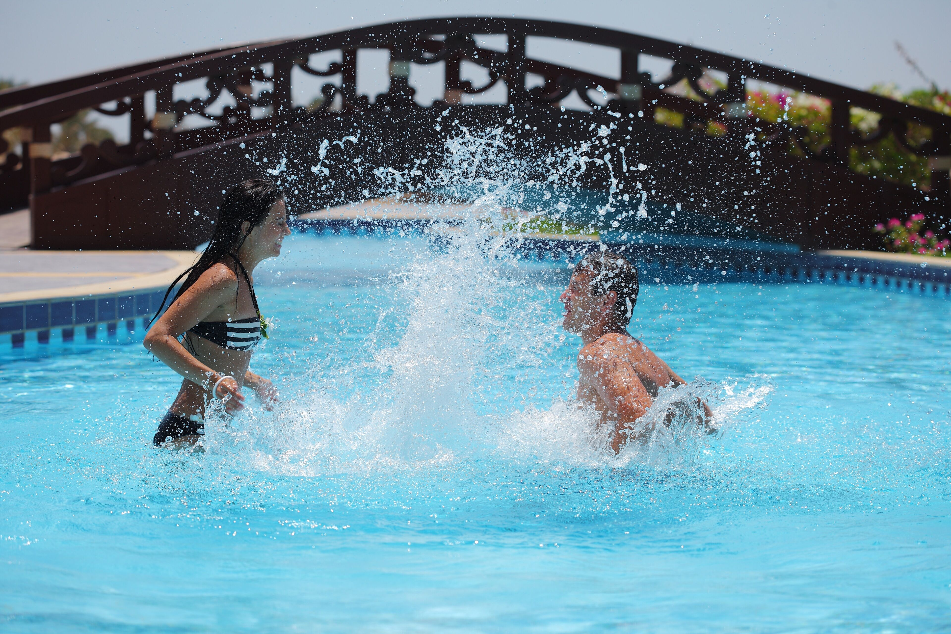 A swimming pool with a decorative bridge in the background.