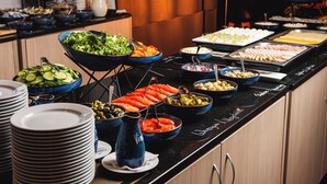 Een buffet met diverse gerechten en een stapel borden.