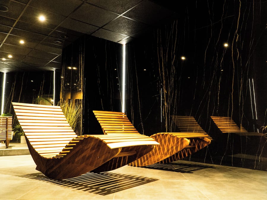 A modern interior with a unique seating area featuring slatted wooden chairs and a geometric floor design.