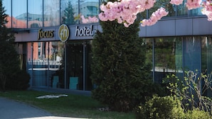 Een modern gebouw met een glazen gevel, een bord met daarop 'focus hotel' en kersenbloesems op de voorgrond.