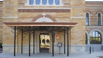 A stone building with a covered entrance and a cross above the door.
