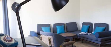 A modern living room with a sofa set, a desk with a lamp, and a vintage telephone.