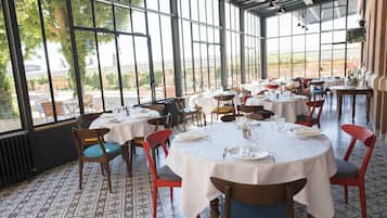 Un restaurante con mesas y sillas redondas, ventanas amplias y baldosas de suelo estampadas.