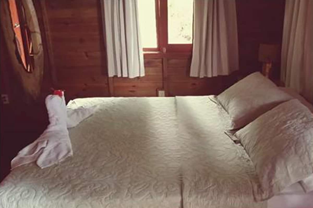 Een houten kamer met een bed, gordijnen en een raam.