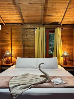 Een houten kamer in chaletstijl met een bed, twee nachtkastjes en een raam met gordijnen.