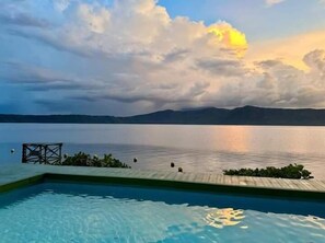 Une piscine avec vue sur un lac paisible et des montagnes lointaines.