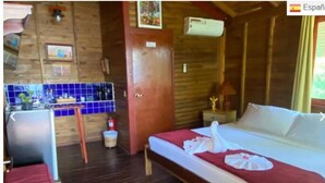 Een houten kamer met een bed, een kleine kitchenette en een badkamer.