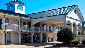 A large, single-story building with a covered patio area and a small tower-like structure. - Americana Inn (Henderson)