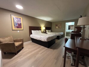 A hotel room with two beds, a desk, a chair, and a couch.