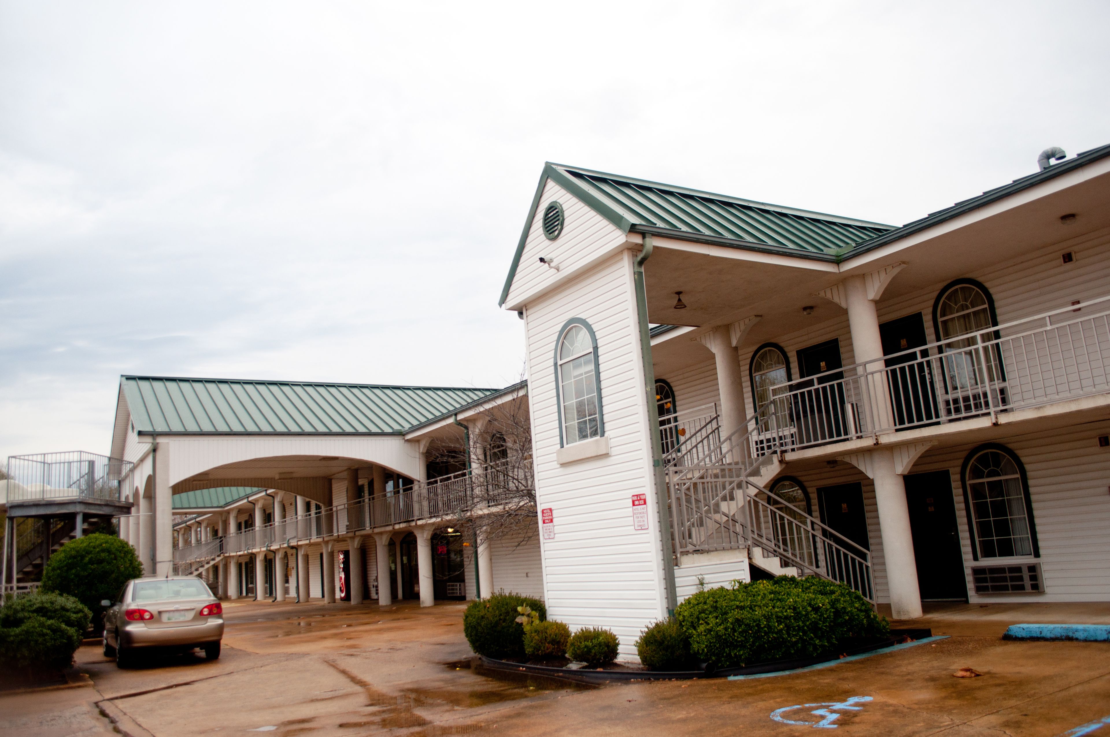 A two-story building with a green roof, multiple balconies, and a covered walkway.