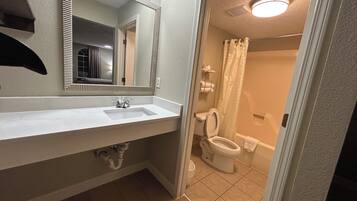 A bathroom with a white sink, mirror, and toilet.