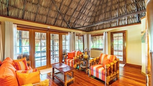 A spacious room with wooden flooring, large windows, and a thatched roof. - Ramon's Village Resort (San Pedro)