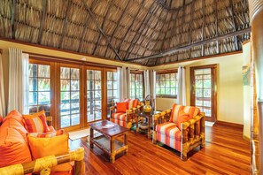 Una habitación amplia con suelo de madera, ventanas grandes y techo de paja.