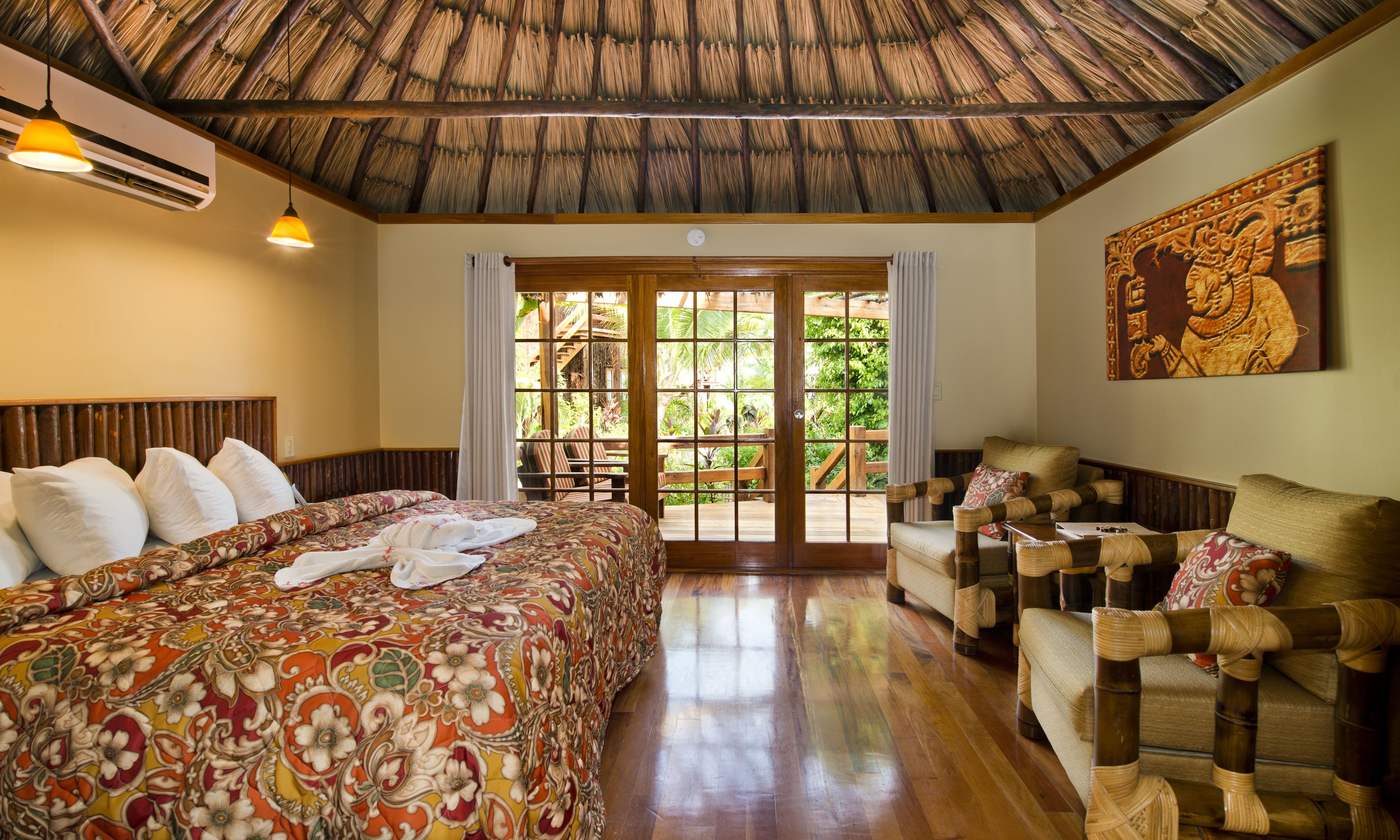 A room with a bed, a seating area, and a large window.