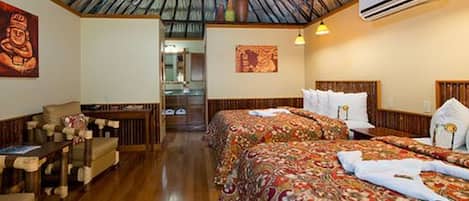 A hotel room with two beds, a wooden ceiling, and a small sitting area with a chair and table.