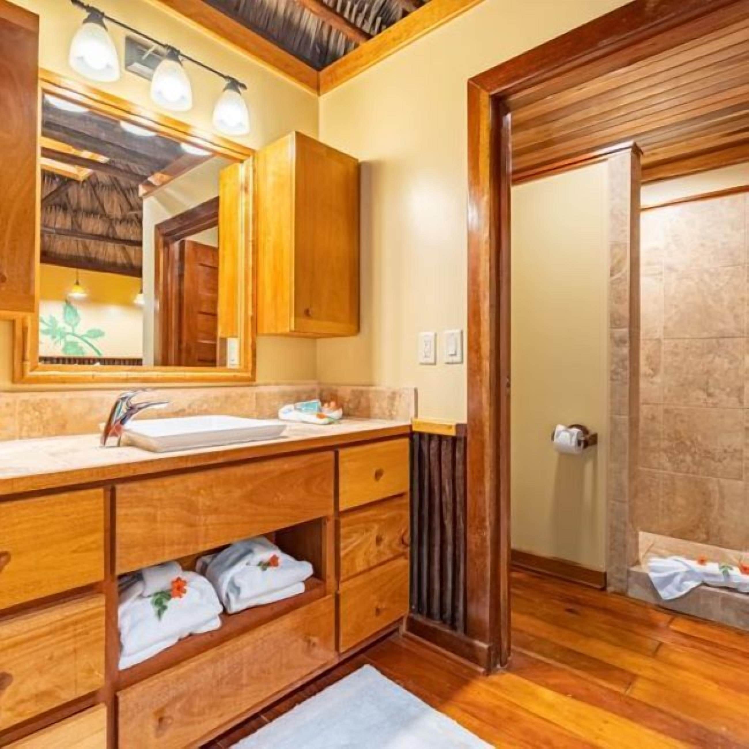 A wooden bathroom with a sink, mirror, and towel storage.