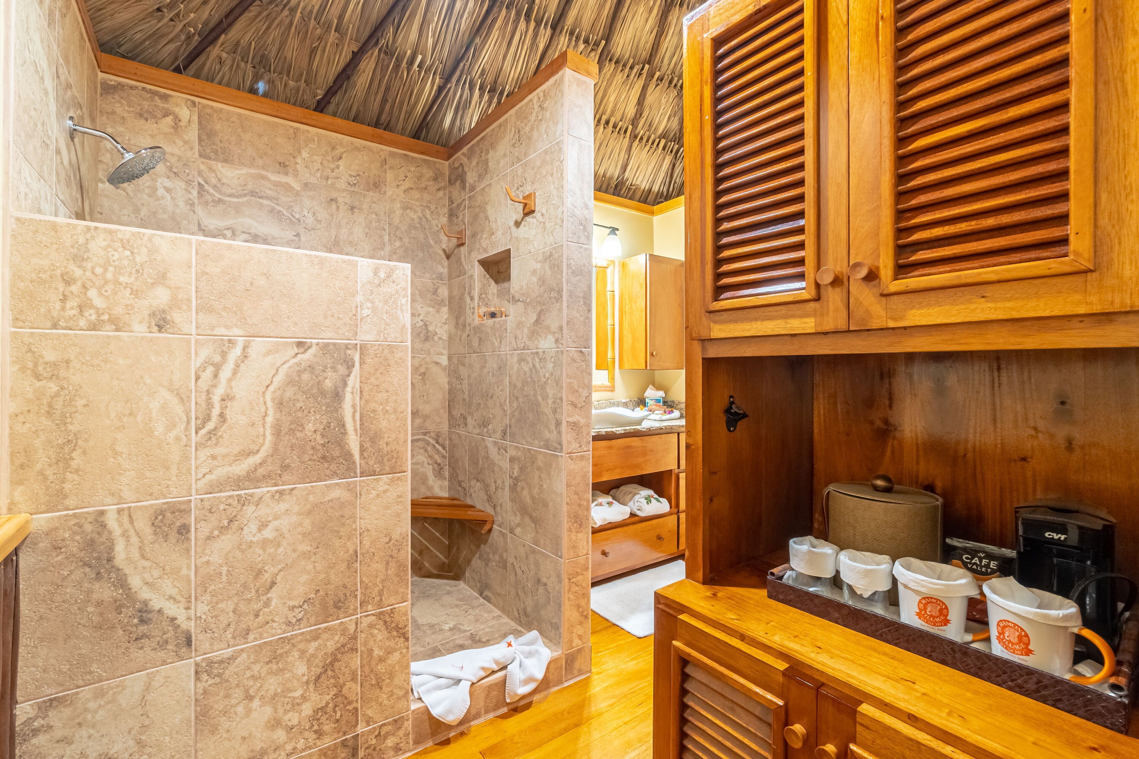 A bathroom with a shower, wooden cabinets, and a coffee station.