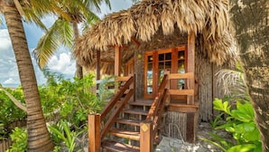 A wooden staircase leading to a thatched-roof structure surrounded by lush greenery. - Ramon's Village Resort (San Pedro)