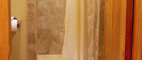A bathroom with a shower, a towel rack, and a wooden floor.