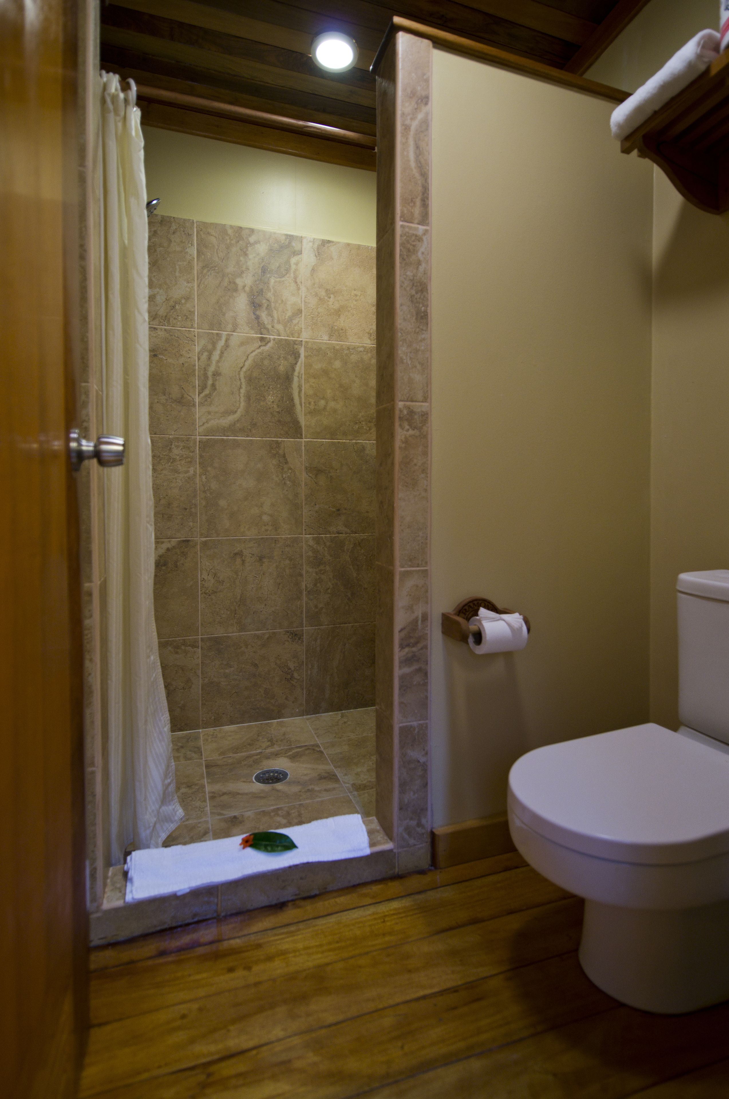 A bathroom with a shower, toilet, and a towel rack.