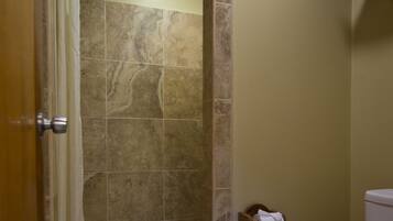 A bathroom with a shower, toilet, and a towel rack.